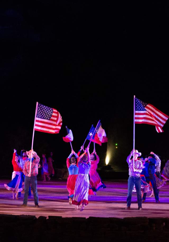 Actors on holding texas flags on stage