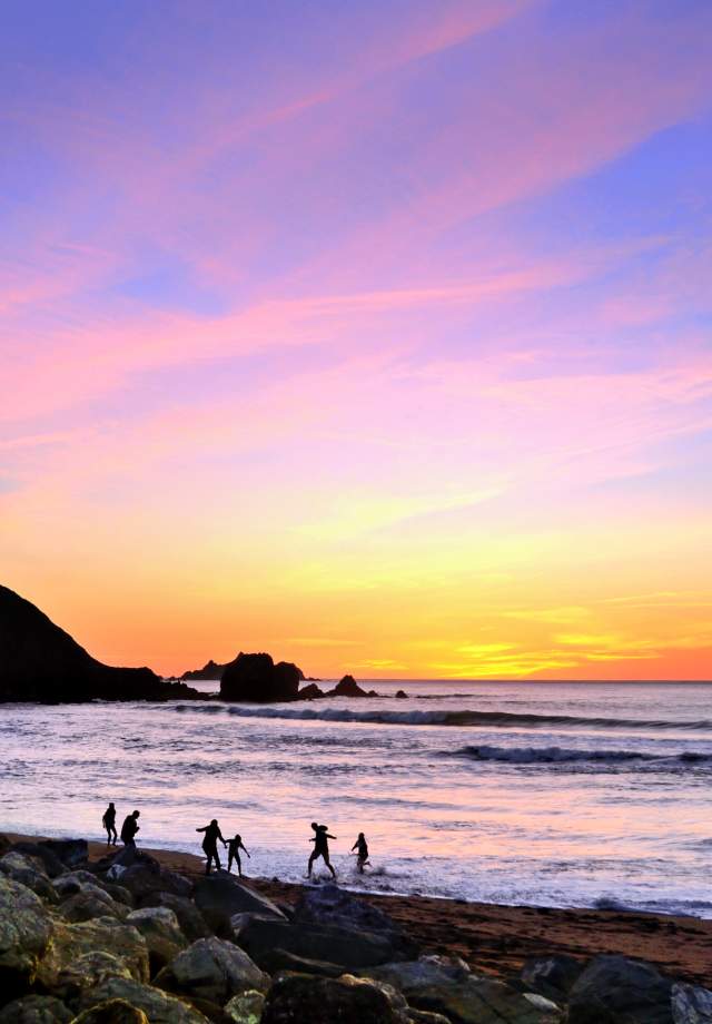 Kids playing at Rockaway Beach during sunset in Pacifica, California.