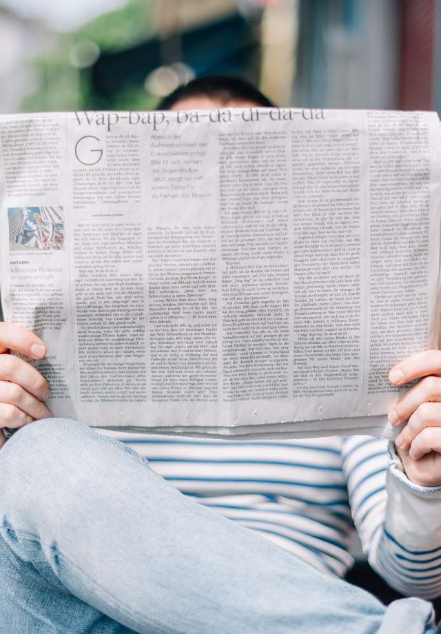 Man reading newspaper sitting on a bench
