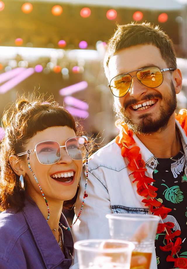 Three women and a man enjoying drinks at a music festival
