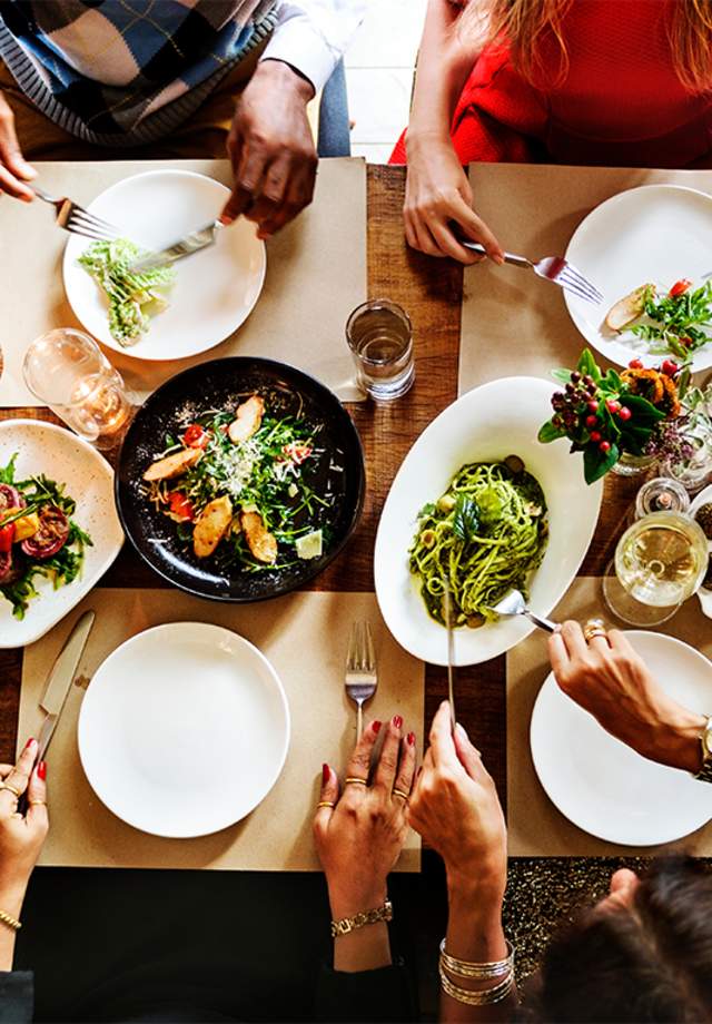 People eating from many plates of food on a table in a restaurant