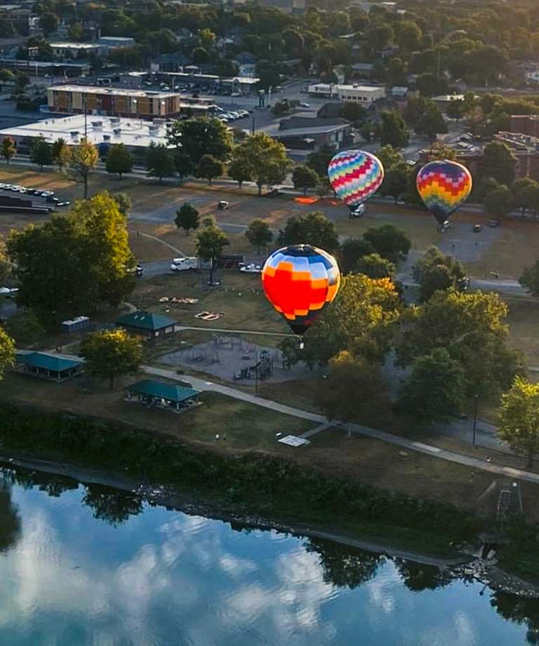 5 hot air ballons floating over the Wabash River, part of the Terre Haute Baloon Festival