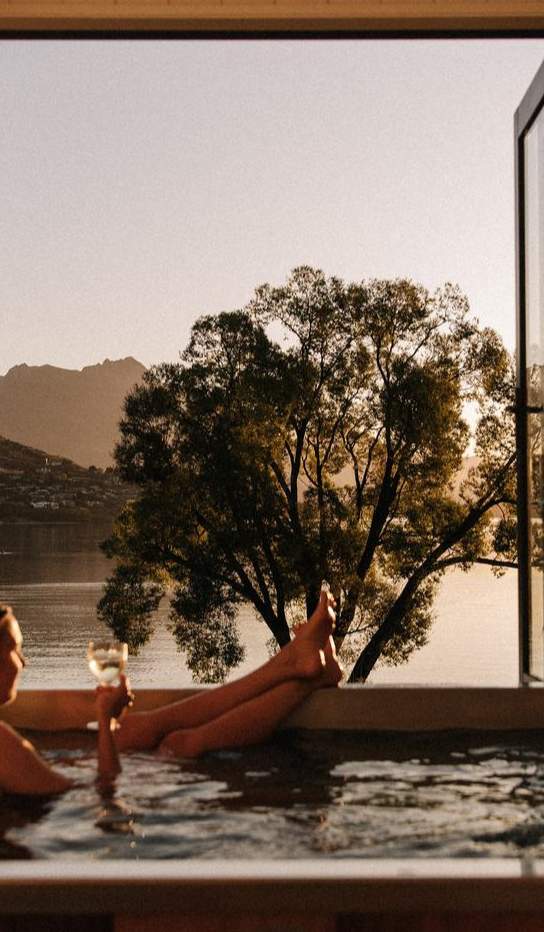 Woman relaxing with a glass of win in a hot tub at Driftaway, Queenstown