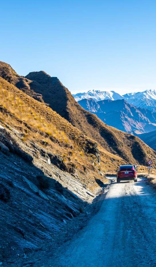 Tesla driving down Skippers Road with mountains in background