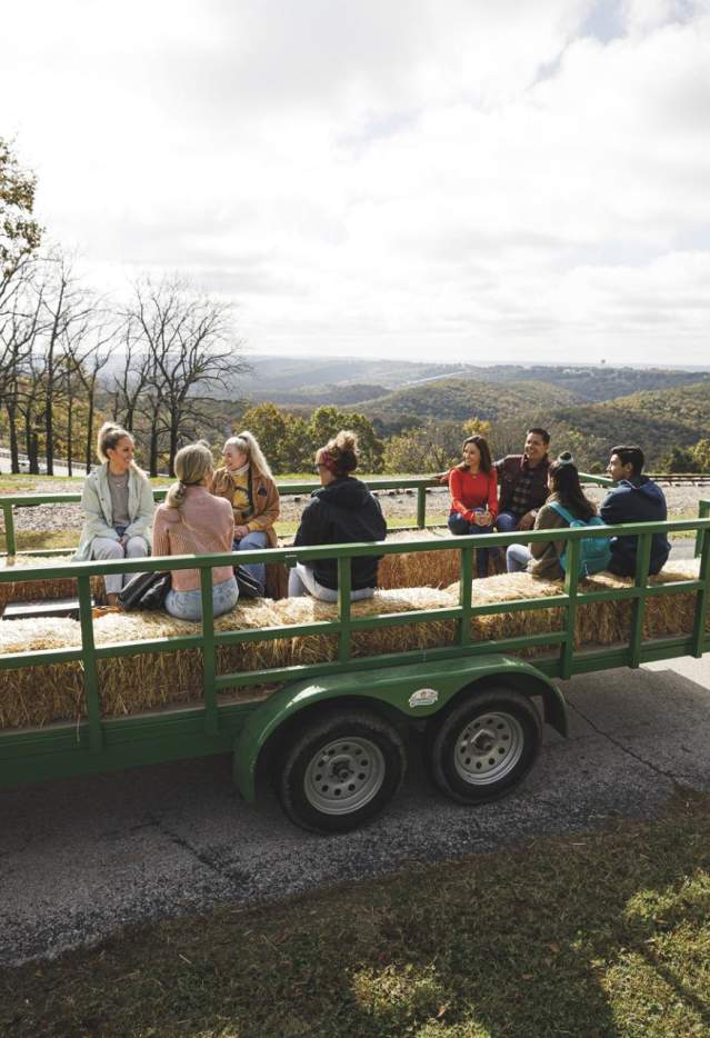 A group riding on a hayride with rolling hills in the background