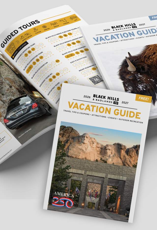 Black Hills & Badlands Vacation Guide with the summer cover, the winter cover, and opened to a page