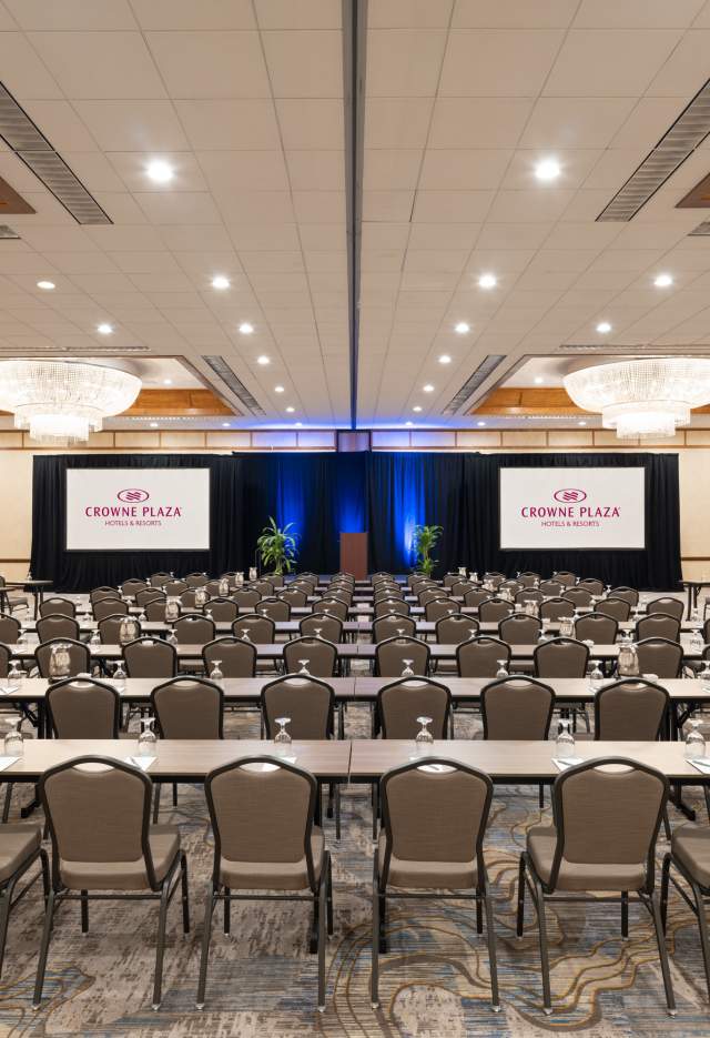 ballroom of the Crowne Plaza Phoenix Chandler Golf Resort set with tables, chairs and screens with overhead chandeliers