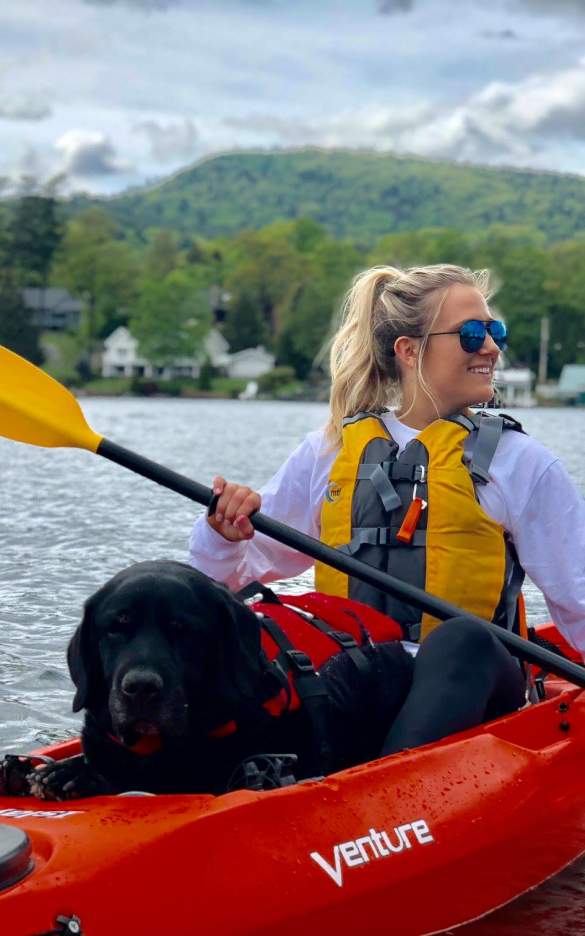 Woman and dog kayaking through lake george