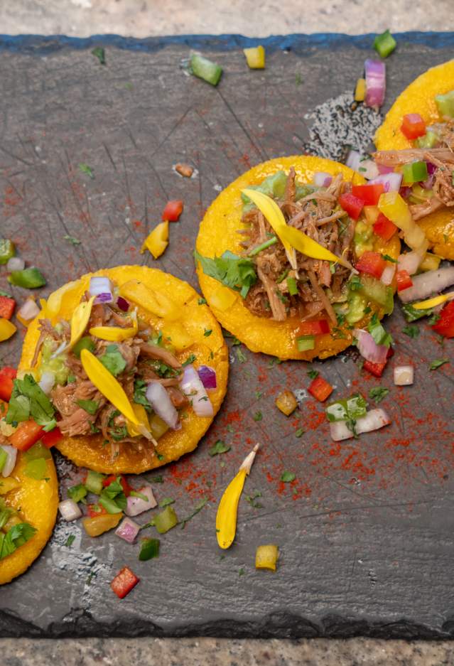 Tacos displayed with colorful garish on a slate
