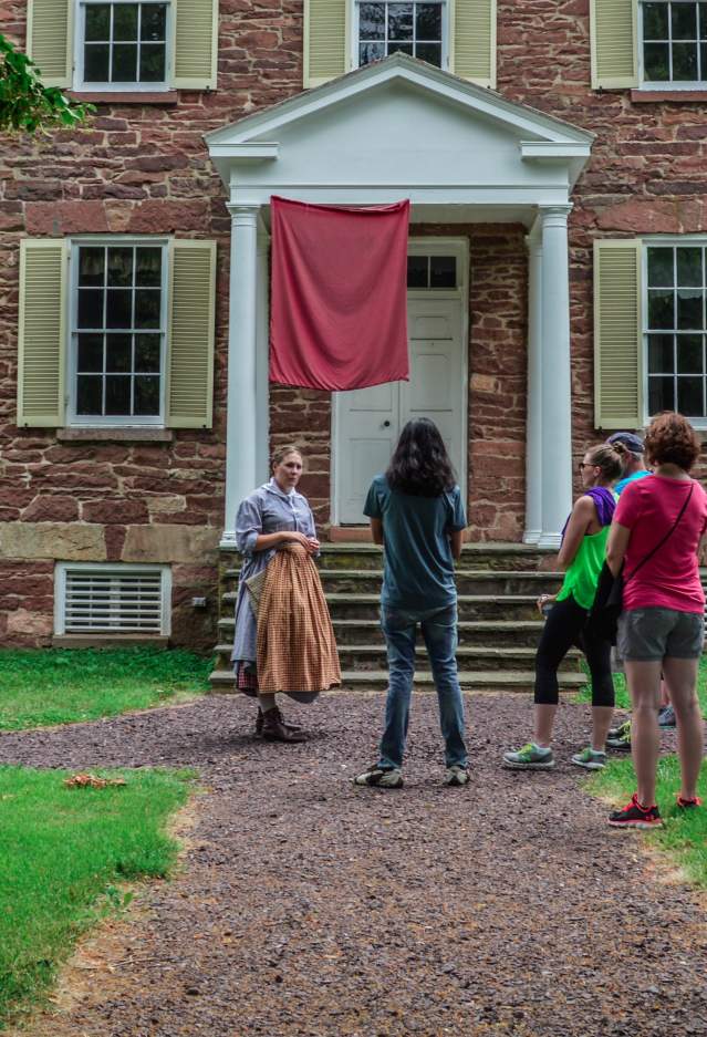 A woman in historic attire tells a story to a group of visitors