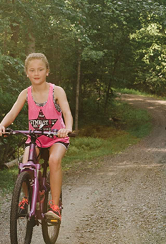 A woman, 2 girls and a man riding bikes on a path in a forest