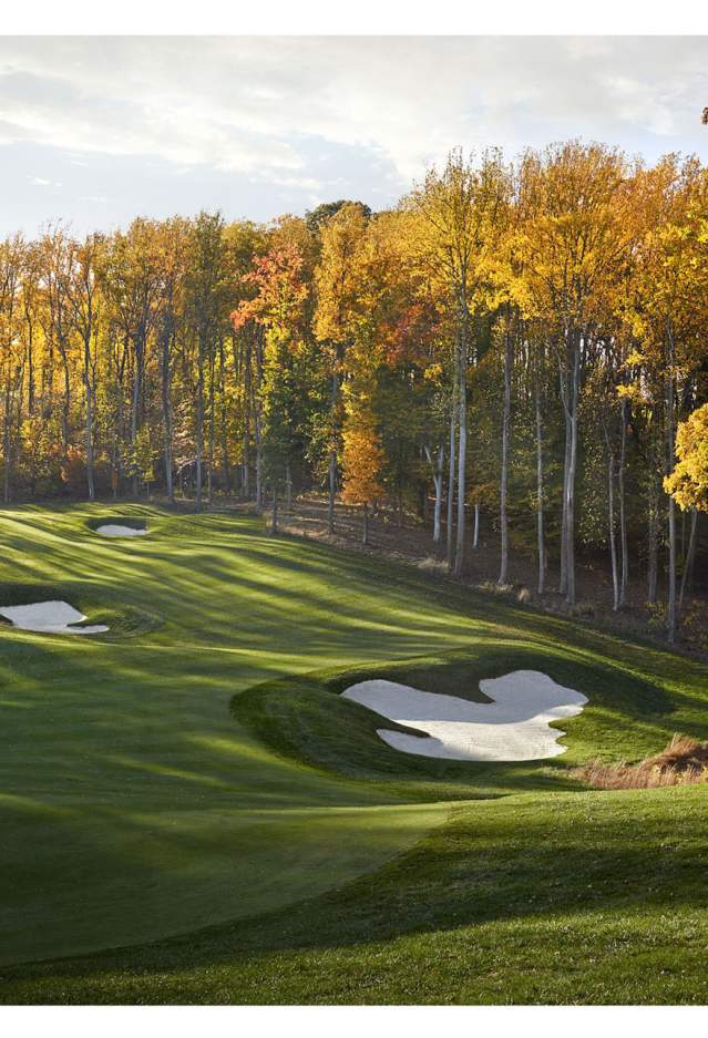 A golf course surrounded by trees with fall foliage