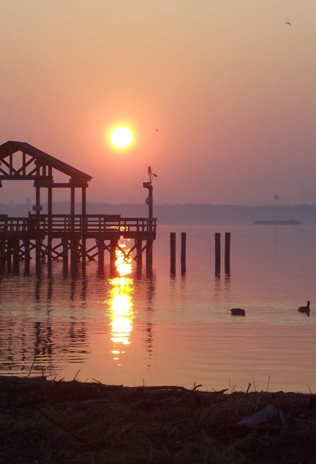 a beach at sunset with a boardwalk in the background