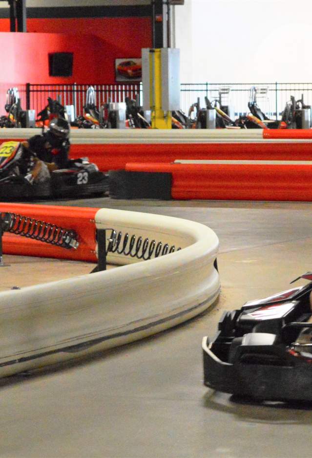 An indoor go-kart facility with 2 go-karters racing
