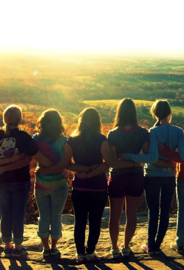 group of women standing together on top of a mountain