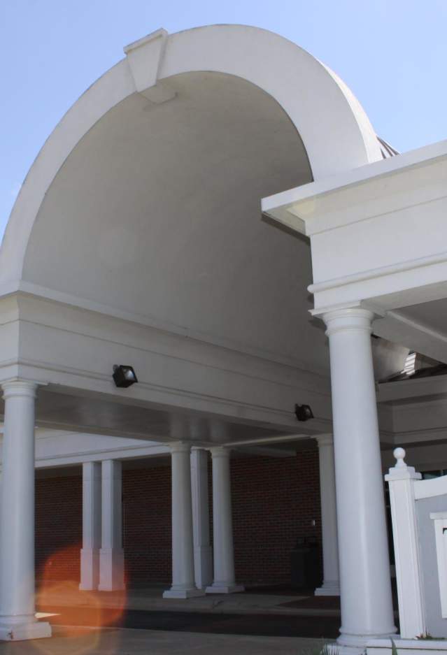 A white and brick building with a sign out front that says "The Clubs at Quantico"