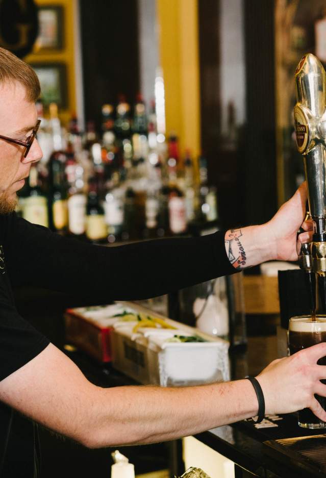 A bartender pouring a glass of beer
