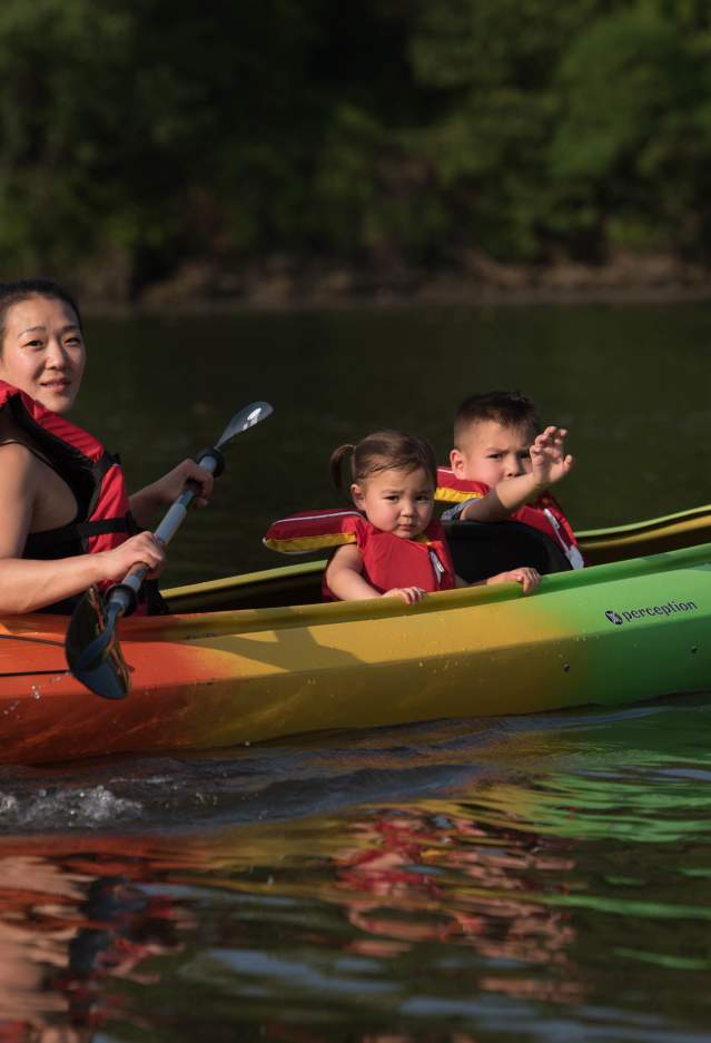 a woman and 2 children kayaking on a river