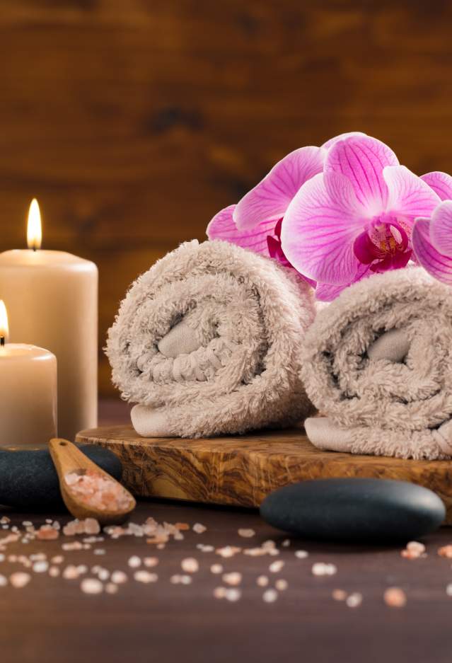 Lit candles, stones, wrapped towels and pink orchids