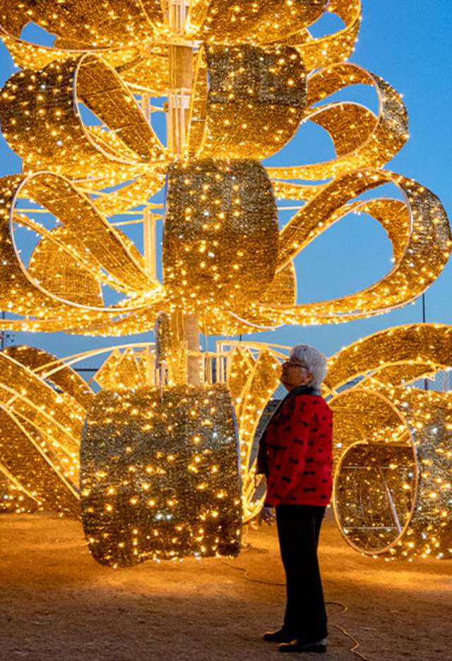 a group of people walking around a lit-up Christmas tree for the Luminance event