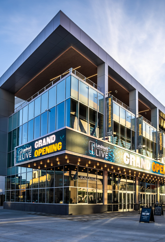 Modern concert venue with a glass facade and large marquee reading “Grand Opening” outside Landmark Credit Union Live in Milwaukee, photographed at sunset with people walking nearby.