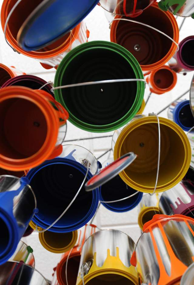 Art installation of multi-colored paint cans hanging from ceiling, photographed from below