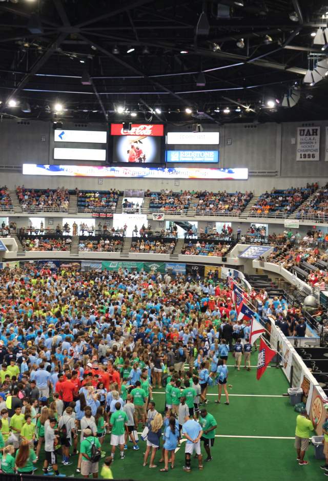 Von Braun Center filled with a diverse crowd of people in colorful shirts, gathered for an event, with extensive seating visible above.