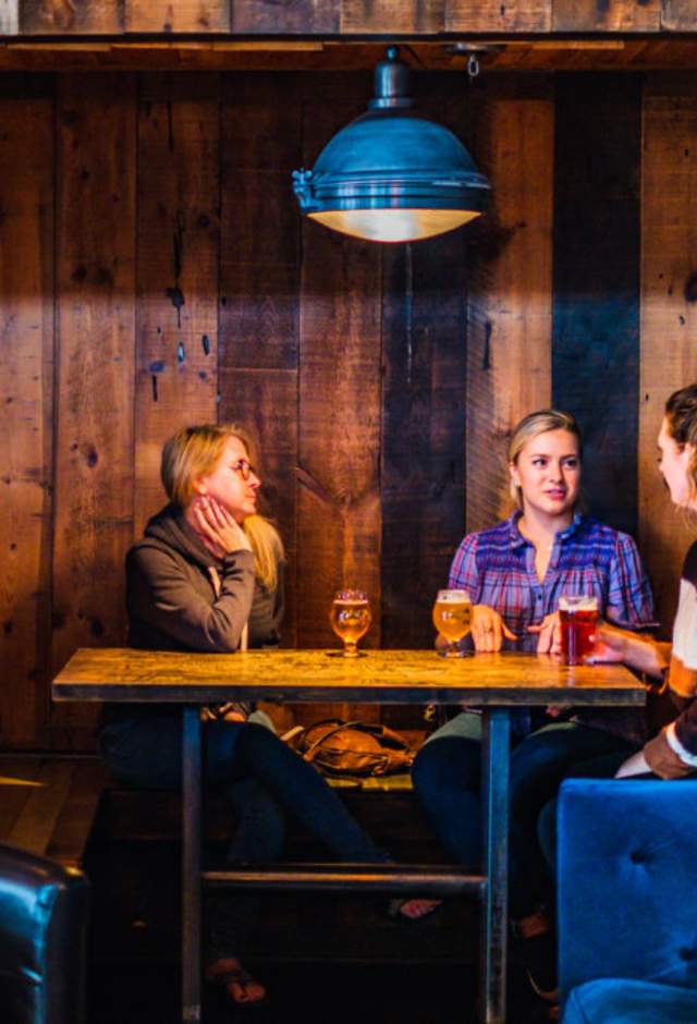 Three people sitting in a booth at Draft & Vessel in Wauwatosa