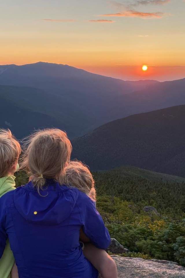 Woman enjoying view of mountain sunset with children