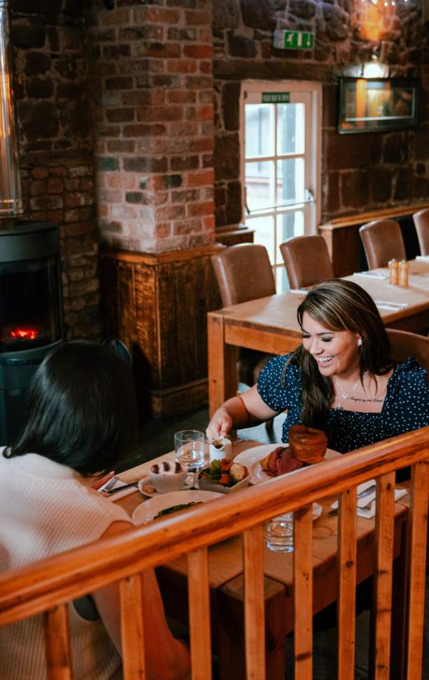 Two women enjoy a meal inside a Wirral pub.