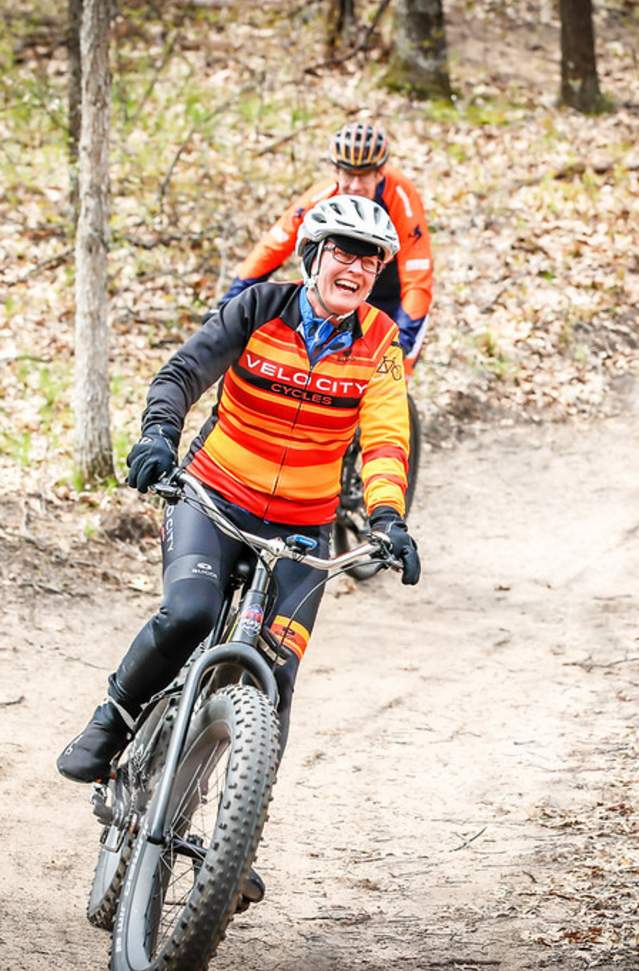 two peddal bikers riding on trail in woods