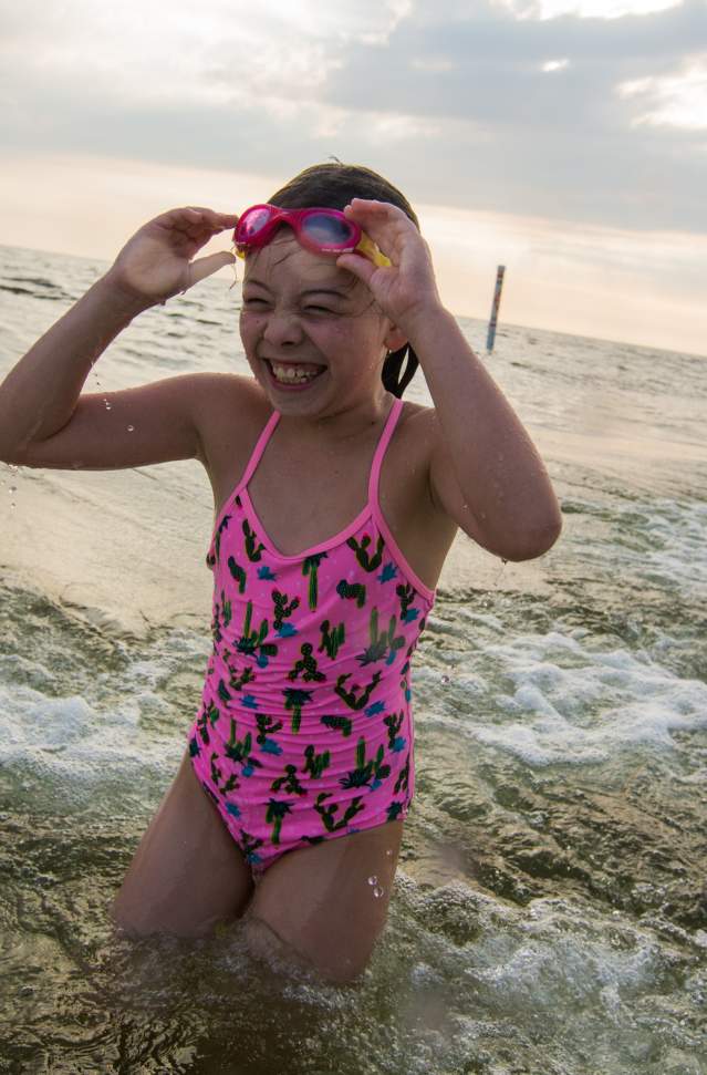 girl with pink bathing suit and goggles coming out of lake michigan