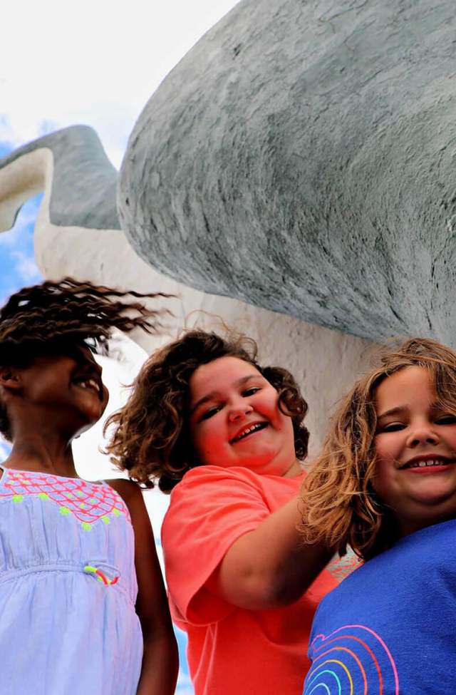 Kids posing for photo below the brontosaurus of Dinosaur Park in Rapid City, South Dakota