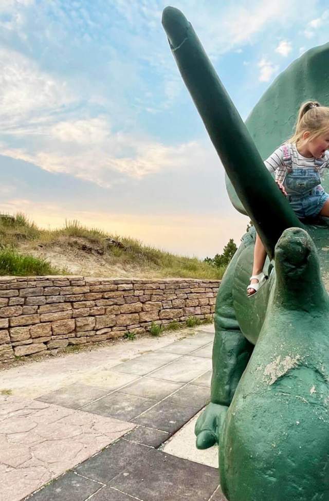 kid climbing on the Triceratops statue found at dinosaur park in rapid city south dakota