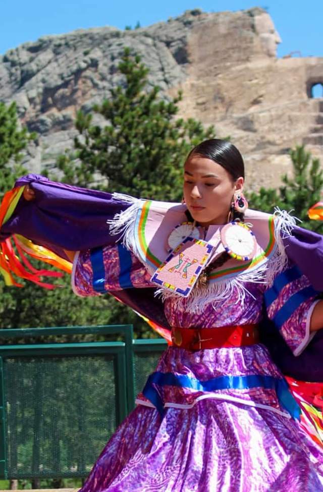 Native American dancer with colorful regalia in front of Crazy Horse Memorial®