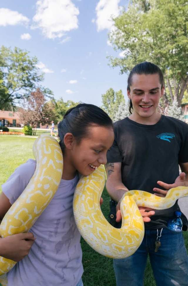 kid holding a python with handler from reptile gardens at the world's largest reptile zoo in rapid city, sd