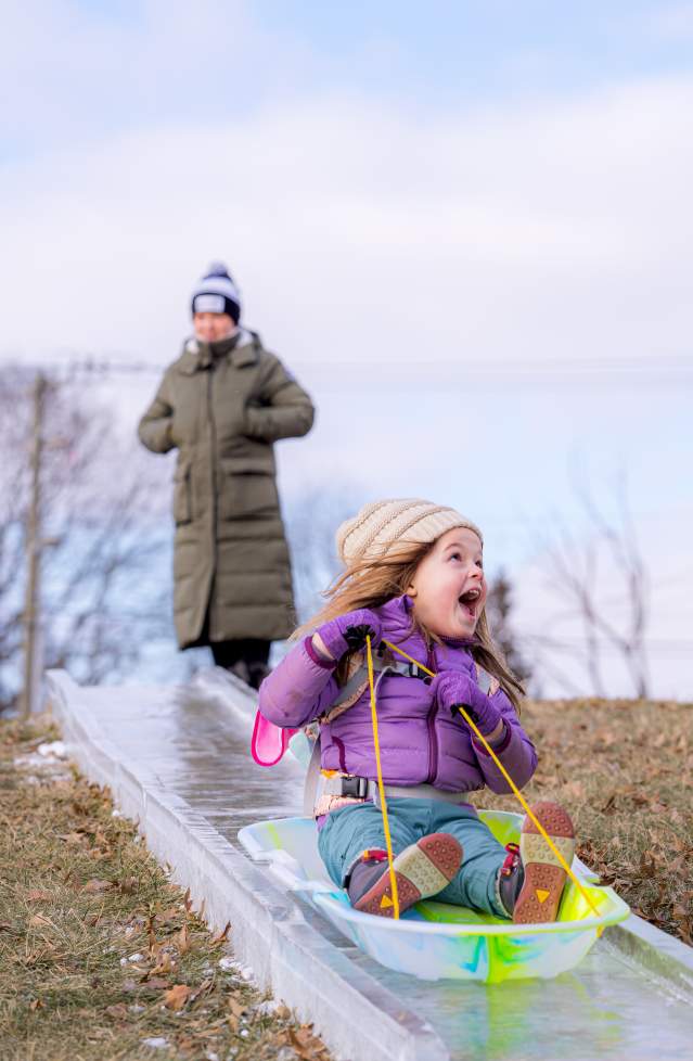 A little girl sledding down the ice luge at Freezefest