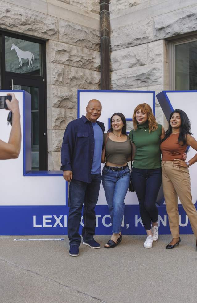 Group of people getting their picture taken in front of a LEX sign.