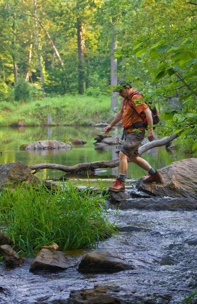 Man hiking across a river in Prince George's County, Maryland