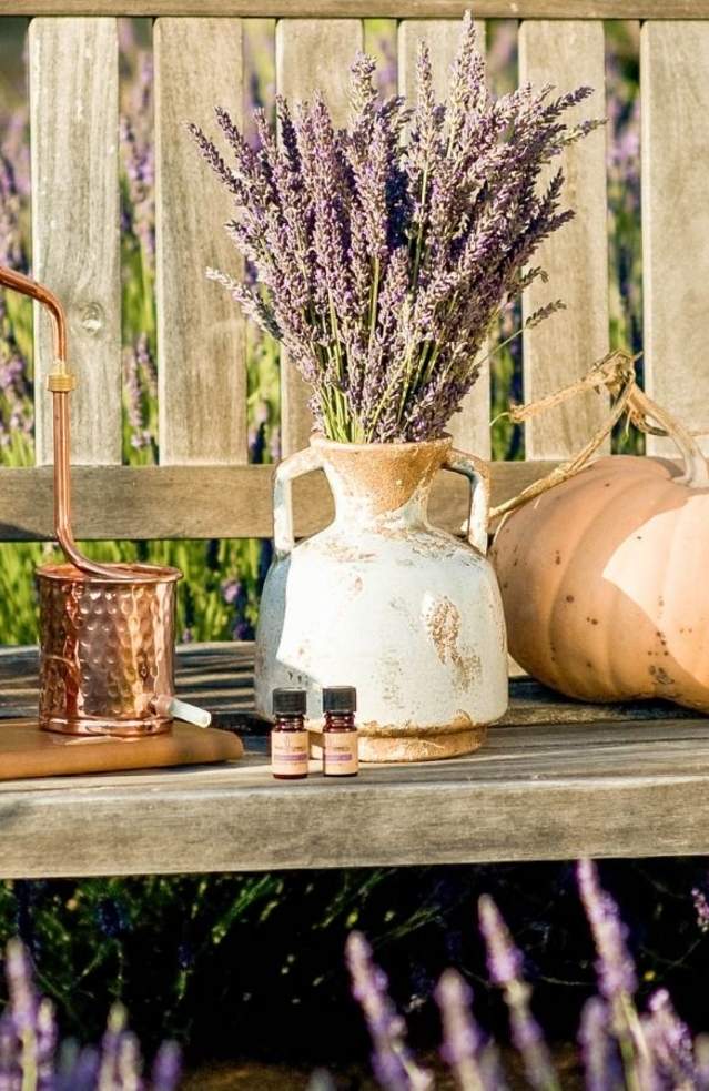 Lavender and copper vases arranged on a rustic wooden bench, showcasing a blend of colors and textures.