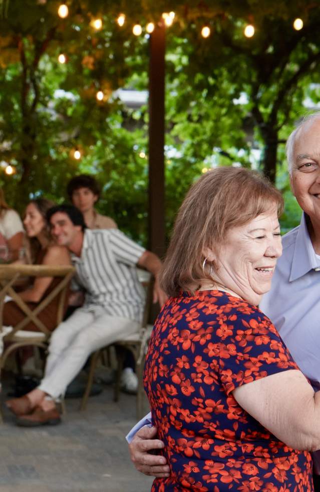 An elderly couple dances together at a winery