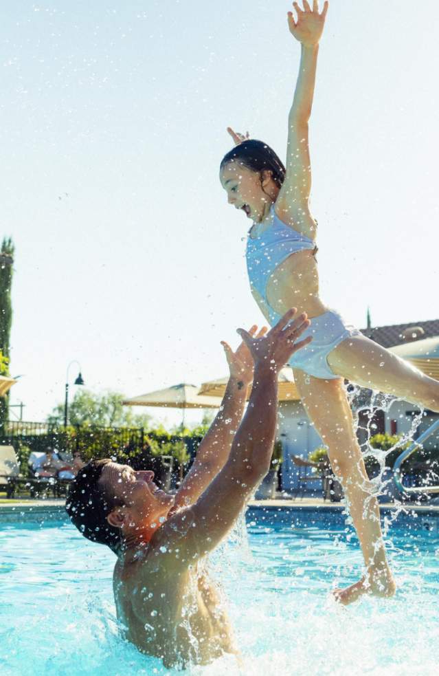 Father and daughter splashing in a pool.