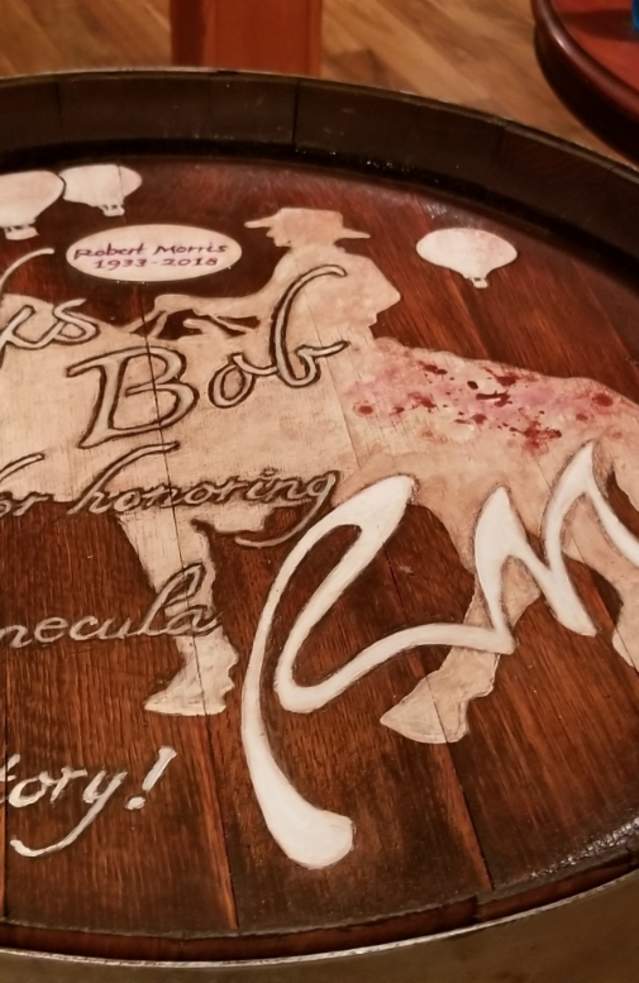 Cowboy riding horse white image hand painted on top of a wine barrel.