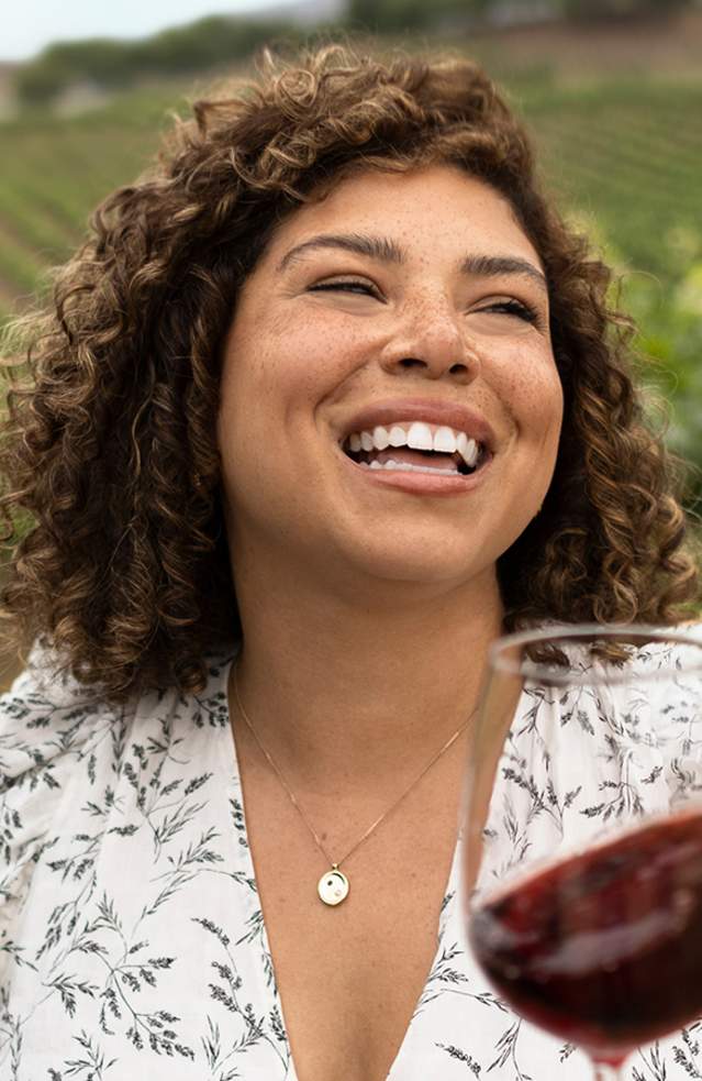 A woman enjoying a glass of red wine at a vineyard