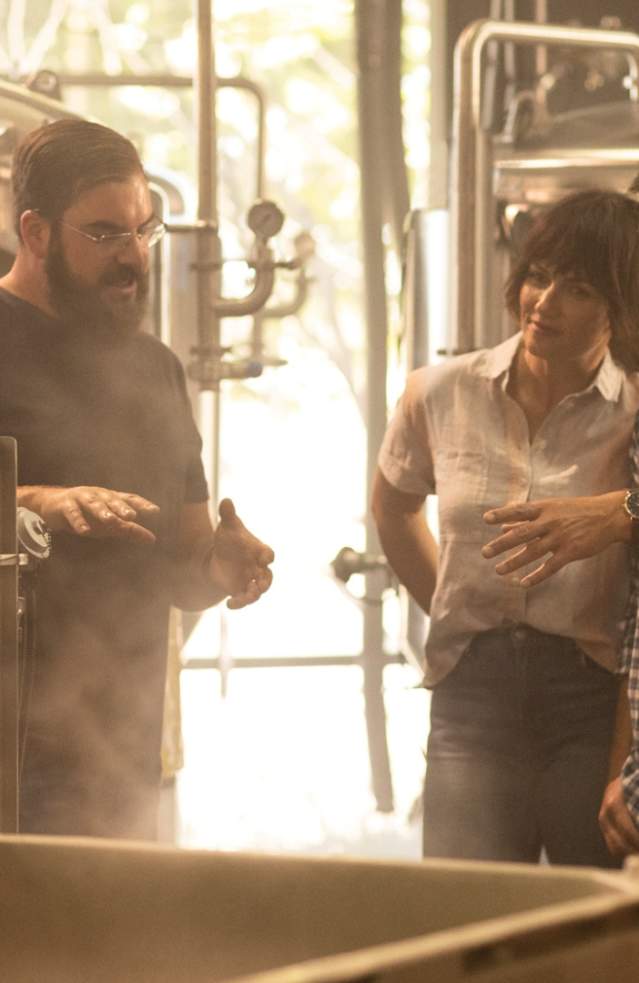 A brewer delivers an informational tour inside the brewery to a man and a woman