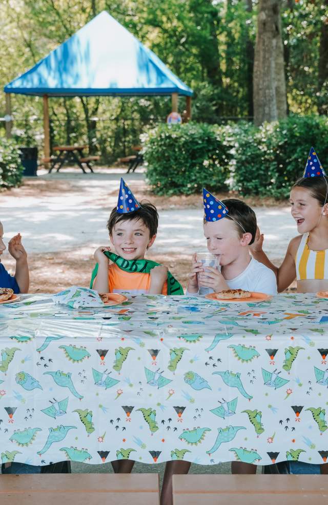 Young boy's birthday party surrounded by friends eating pizza.