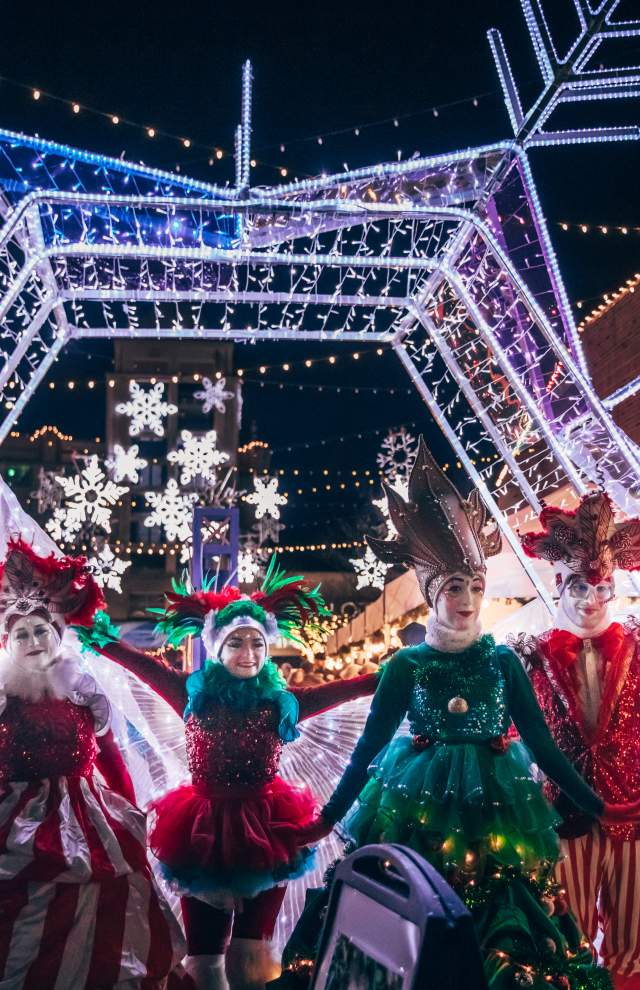 6 entertainers pose in winter costumes at night with Christmas lights