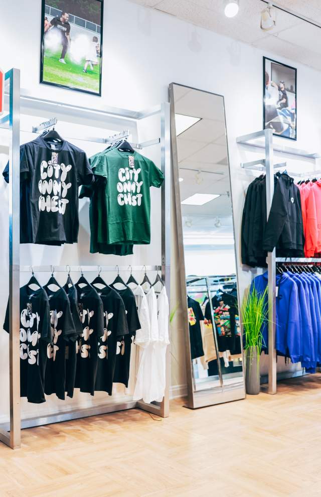 A retail shop with tshirts that read: City On My Chest are set out alongside a basketball hoop in a mall storefront