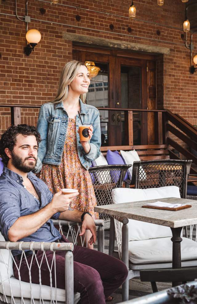 A couple holds beverages on an outdoor patio