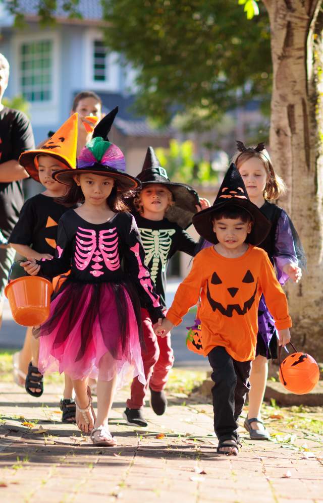 Family dressed up for Halloween walking down the sidewalk to go to Trick or Treat Street